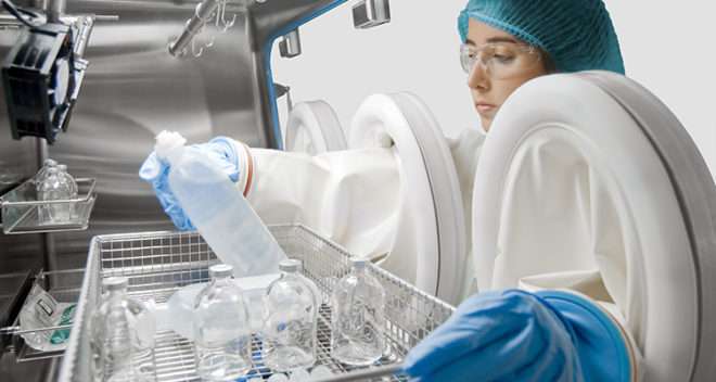 Female scientist using a dual chamber sterility test isolator