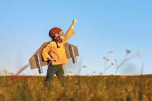 Child pilot aviator with wings of airplane dreams of traveling in summer in nature at sunset