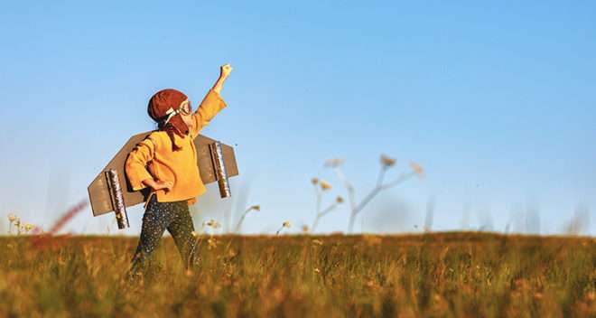 Child pilot aviator with wings of airplane dreams of traveling in summer in nature at sunset