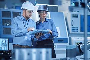 Professional Female Engineer, Male Machinery Operator Use Industrial Digital Tablet Computer to Work and Program Robot Arm for Production Line.