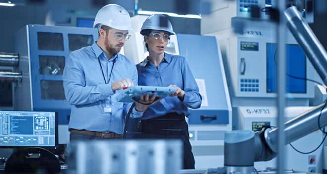 Professional Female Engineer, Male Machinery Operator Use Industrial Digital Tablet Computer to Work and Program Robot Arm for Production Line.