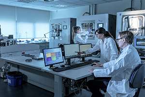 A team of scientists in lab coats working diligently on computers in a research laboratory.