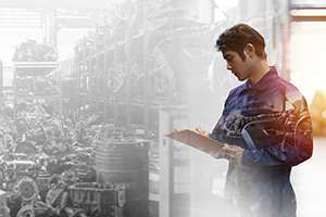 Male engineer checking old engine, motor, machine at the garage industry factory, noting the defects found.