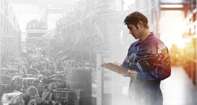 Male engineer checking old engine, motor, machine at the garage industry factory, noting the defects found.