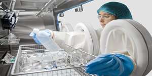 Female scientist using a dual chamber sterility test isolator