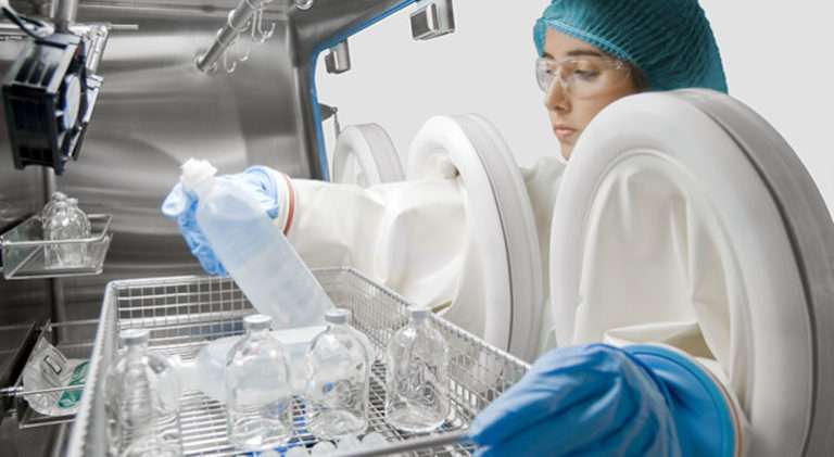 Female scientist using a dual chamber sterility test isolator