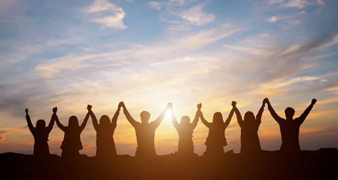 Silhouette of people raising hands at sunset, expressing joy and unity in a beautiful outdoor setting.